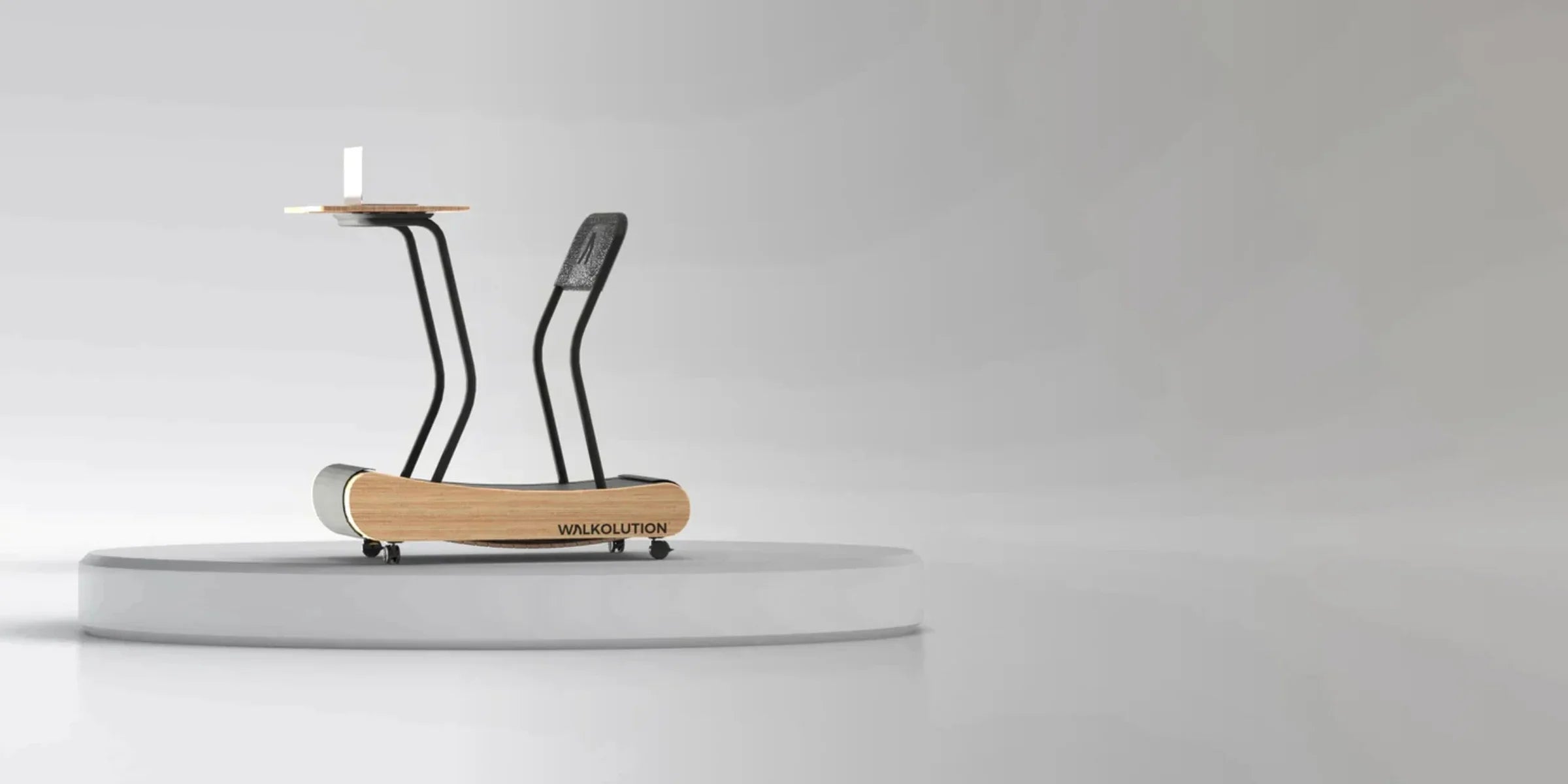 A minimalist treadmill desk with a wooden base, black frame, mesh chair, and small tabletop with a cup, displayed on a round white platform against a plain light gray background.