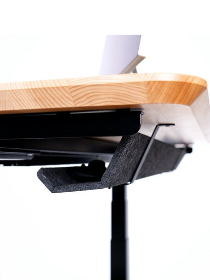 Close-up of the Walkolution Core Desk’s underside, showing its solid beech wood top in a light finish, sturdy black metal legs, a black felt cable management tray, and a laptop placed on the desk.