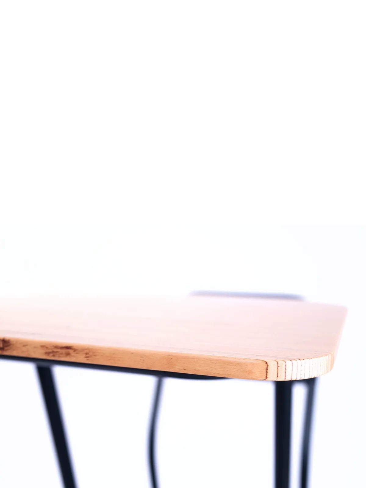 Close-up of a wooden table corner with a light top and black metal legs, designed as an ergonomic workstation ideal for pairing with the Walkolution 1 Desk Attachment, set against a plain white background.