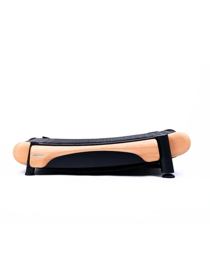 The Walkolution 2 is a wooden and black plastic balance board with a curved base for stability exercises, ideal for use with a manual office treadmill to walk while you work. Shown on a white background.