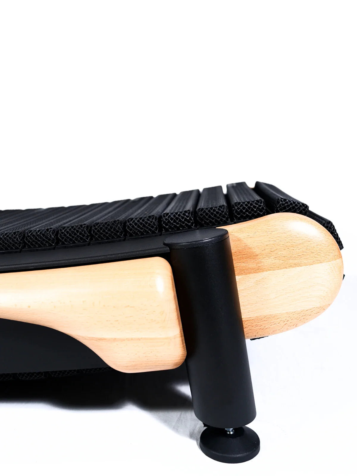 Close-up of the TheraFloor® Home Upgrade-Kit for Walkolution 1: features light wood legs, a black cylindrical support, and a ribbed black cushion resembling a treadmill mat, set against a white background.