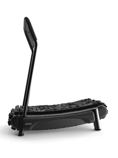 The Walkolution 2 pairs perfectly with a modern, minimalist bench featuring a curved black frame, one angled backrest, a woven black seat, and three short cylindrical legs—ideal for walking stylishly while you work.