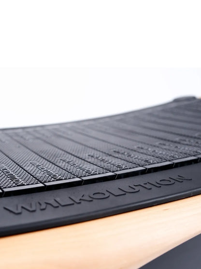 Close-up of the black, textured belt on the Walkolution 2 manual office treadmill. Light wood accents beneath the belt stand out against a plain white background—ideal for walking while you work.