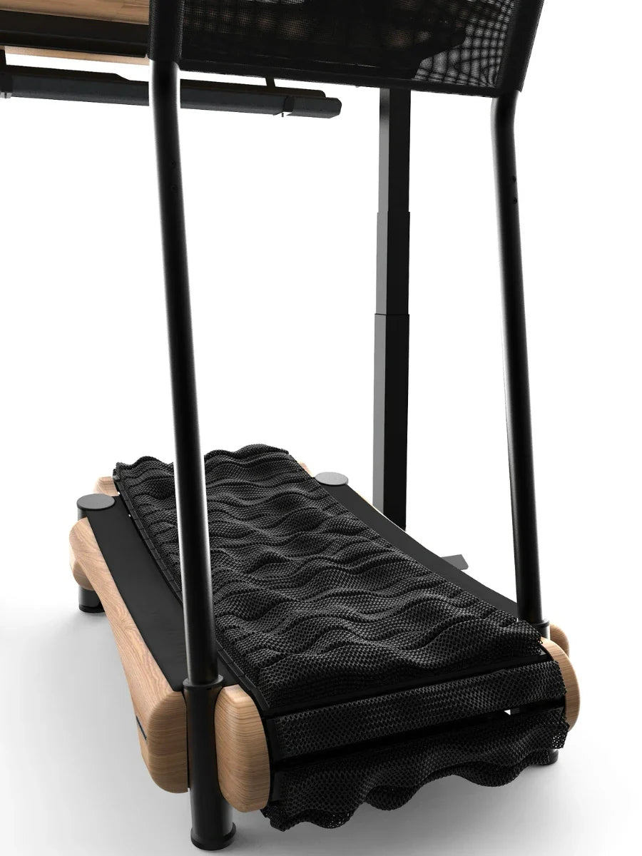 Close-up of a compact, modern treadmill with a wooden frame and wavy, black mesh running belt, partially positioned under a piece of furniture with black legs. Walkolution Global