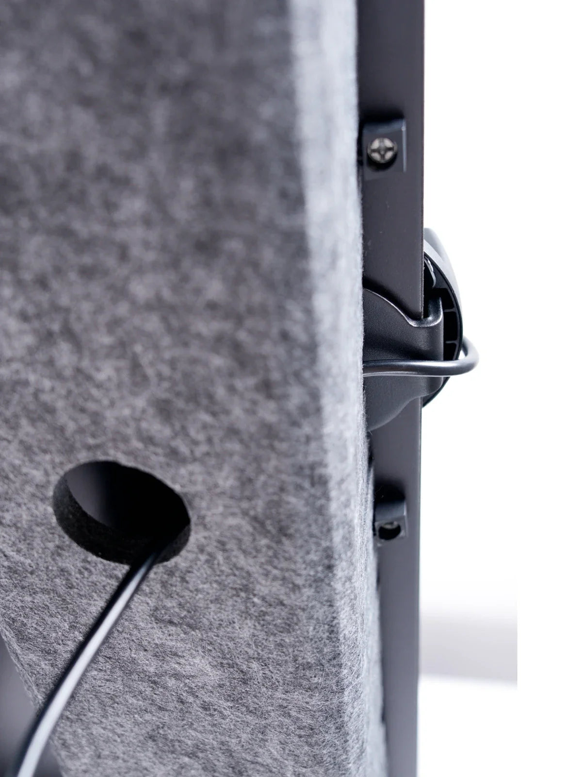 Close-up of the Walkolution Pro Desk Cable Organizer: a gray felt panel with a circular opening, showing black cables passing through a cable tray and connecting to devices for improved workspace organization.