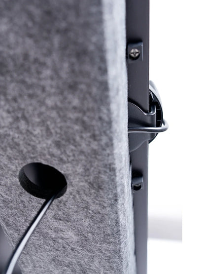 Close-up of the Walkolution Pro Desk Cable Organizer: a gray felt panel with a circular opening, showing black cables passing through a cable tray and connecting to devices for improved workspace organization.