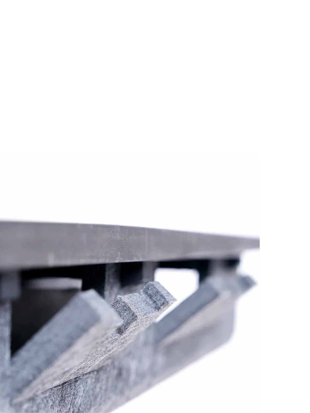 Close-up of the edge and underside of the Walkolution Pro Desk Cable Organizer, featuring eco-friendly materials and grooved, angled support structures, photographed against a white background.