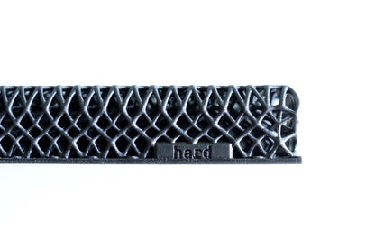 A close-up of a black, lattice-like 3D-printed structure labeled "hard," from the All Surfaces Sample Box, showcasing one treadmill surface sample against a white background.