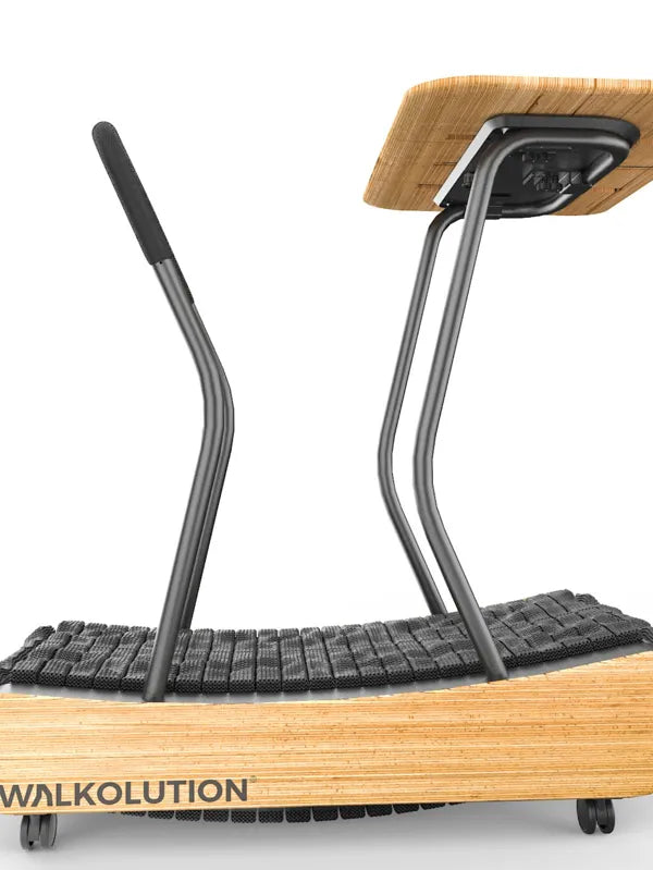 A manual treadmill with a wooden base, black slatted running surface, metal handlebars, and an attached wooden desk. The word Walkolution is visible on the side. Walkolution Global