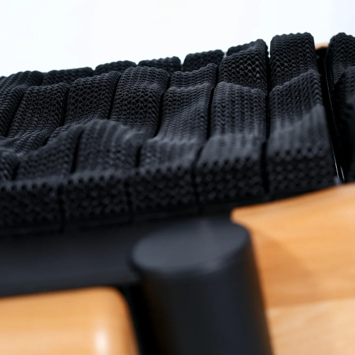 Close-up of a modern chair seat with interwoven black mesh straps and a light wood frame, highlighting the textured pattern and unique design. Walkolution Global