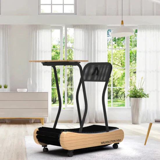 A modern treadmill desk with a wooden base, black frame, and attached tabletop is placed in a bright living room with large windows, white curtains, and minimalist decor.