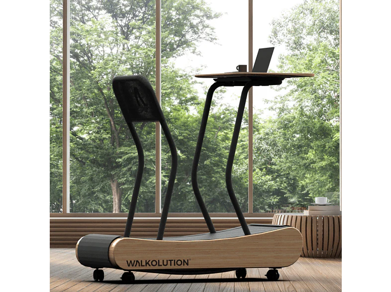 A modern treadmill with a built-in wooden desk holds a laptop, placed in a bright room with large windows and a view of green trees outside. The treadmill is branded WALKOLUTION.
